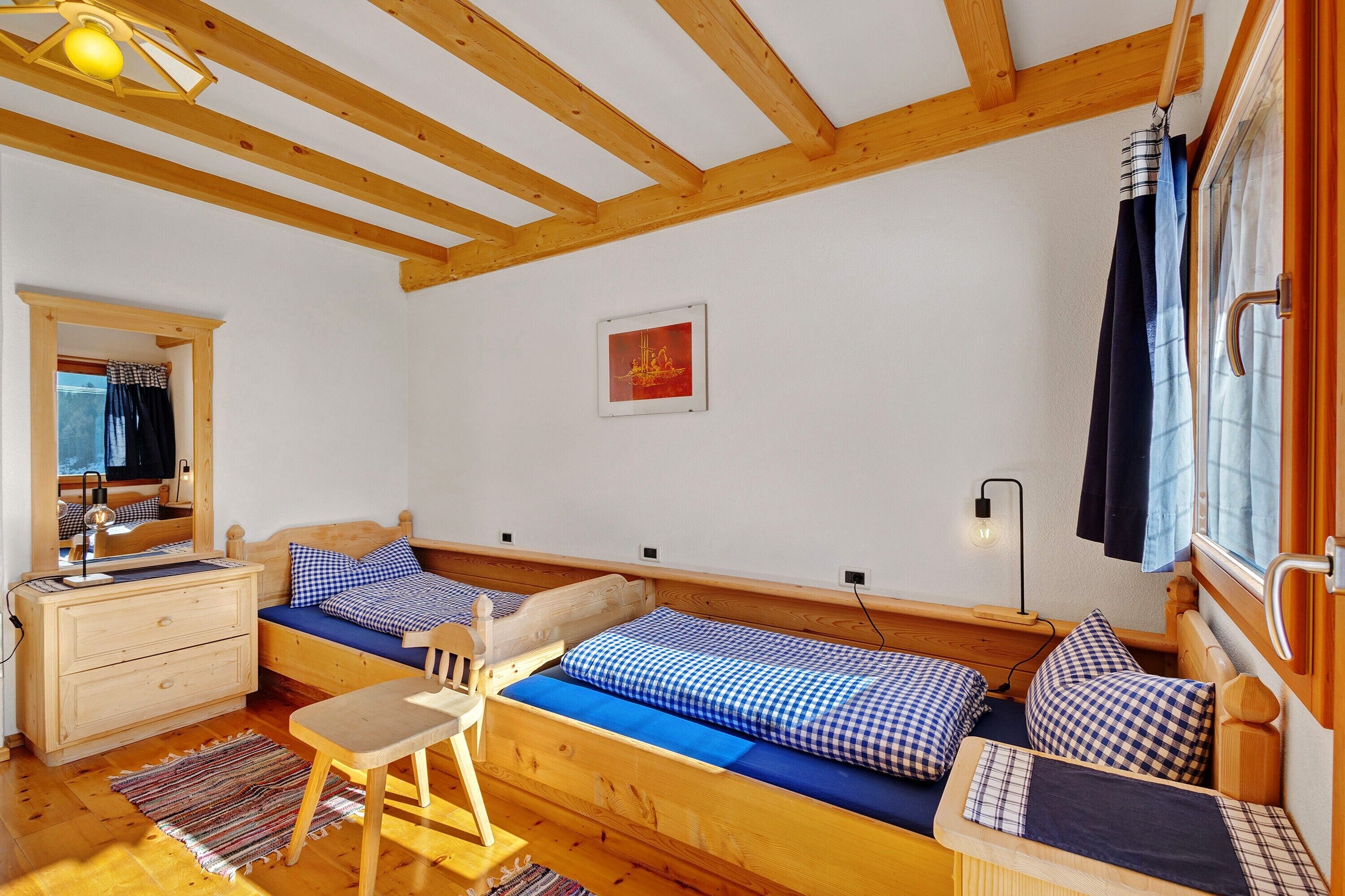Ein Zimmer mit einem hölzernen Bett, einem Holzstuhl, einem Schminktisch und einem Spiegel.