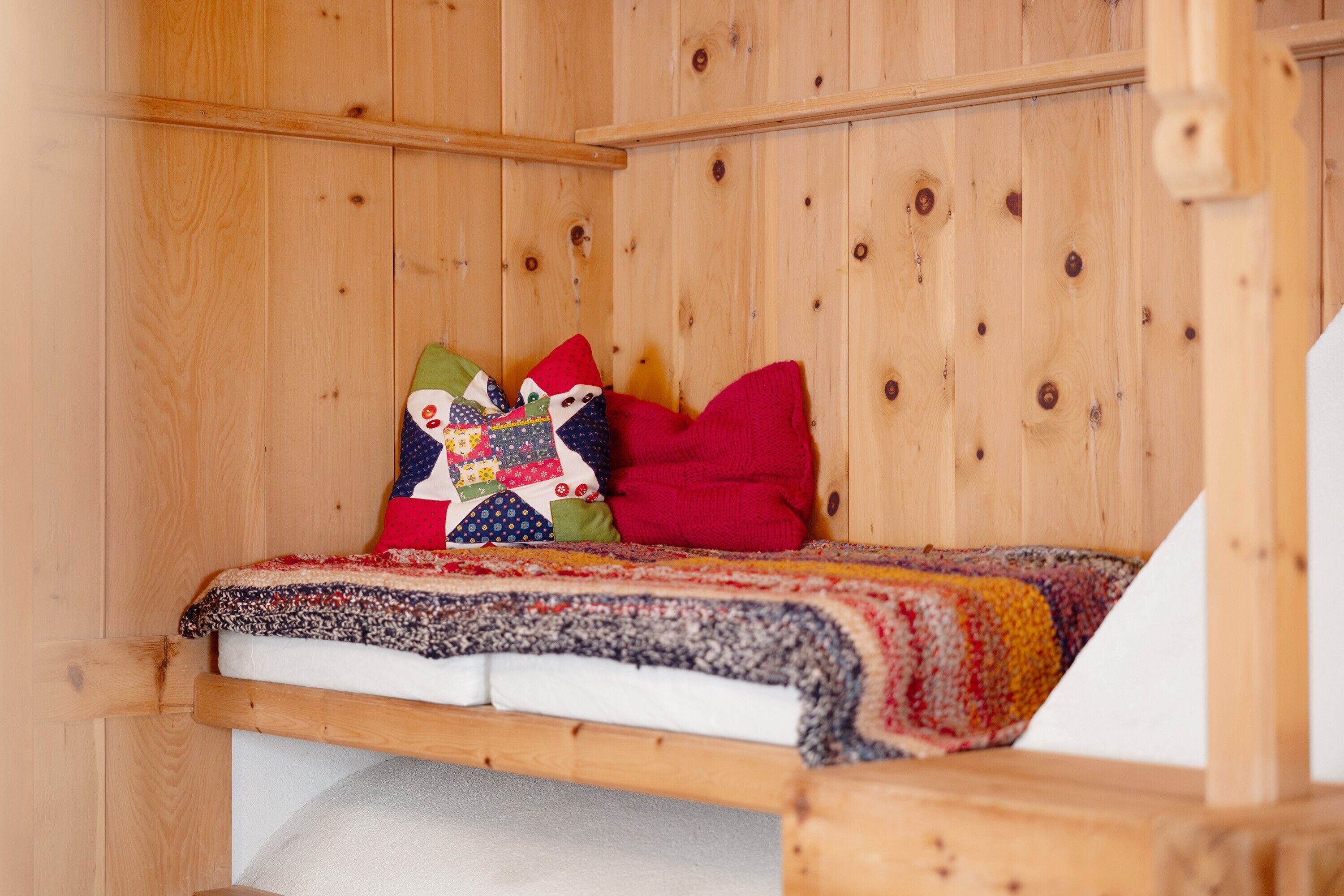 Ein holzgetäfeltes Zimmer im Blockhausstil mit einem Bett, Kissen und einer Steude.