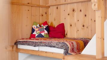 Ein holzgetäfeltes Zimmer im Blockhausstil mit einem Bett, Kissen und einer Steude.