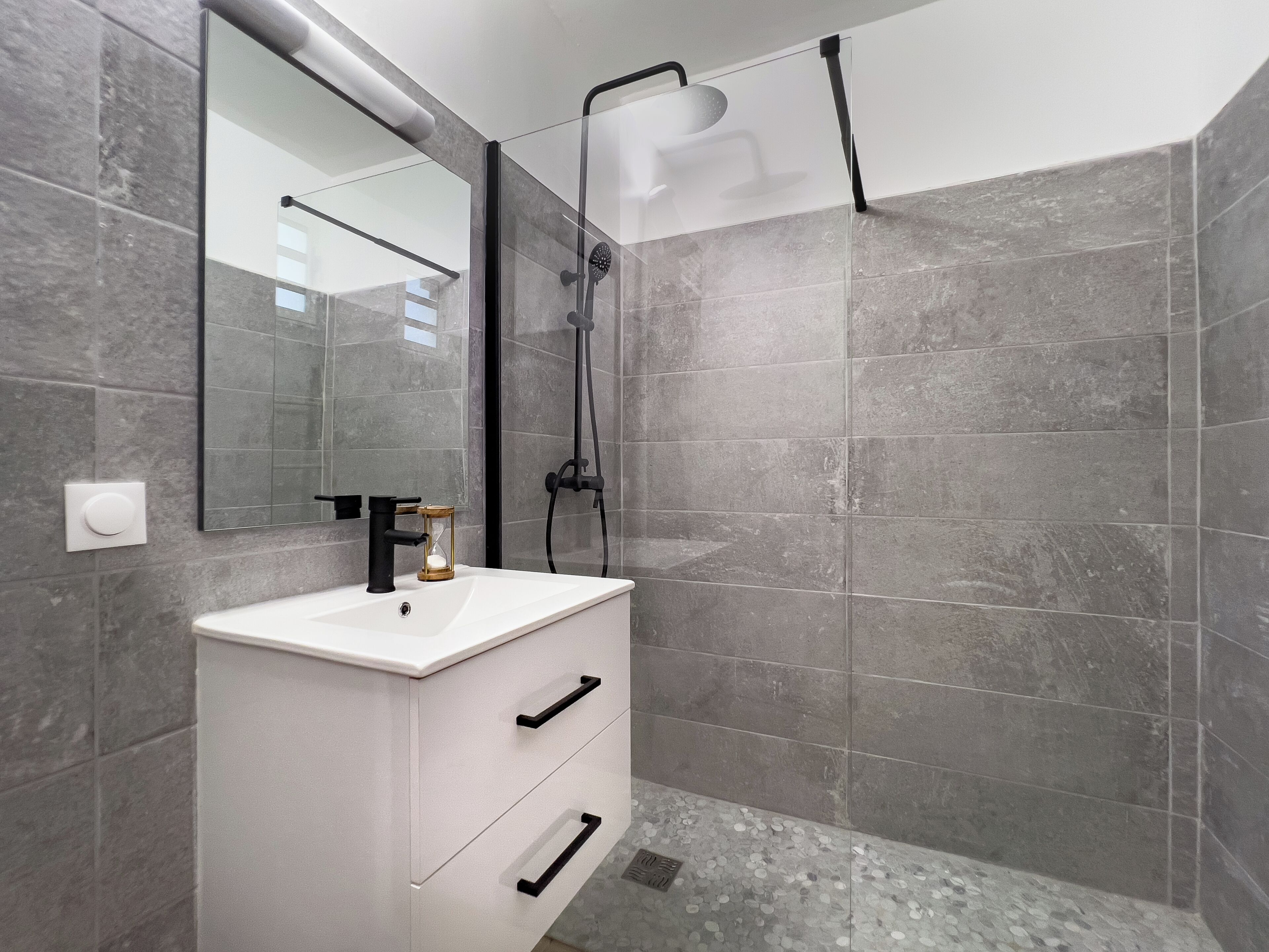 A modern bathroom with a white vanity, a large mirror, and a glass-enclosed shower area.