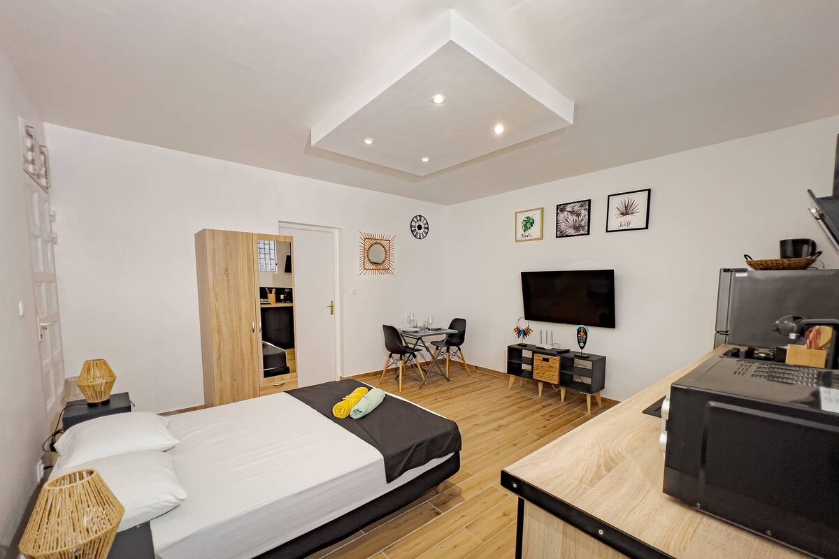 Un dormitorio moderno con cama, escritorio, televisión y kitchenette.