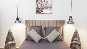 A bedroom with a bed, two pillows, a wall-mounted picture, and two pendant lights. - Habitation Yucca à 5 min de la plage (Le Moule)