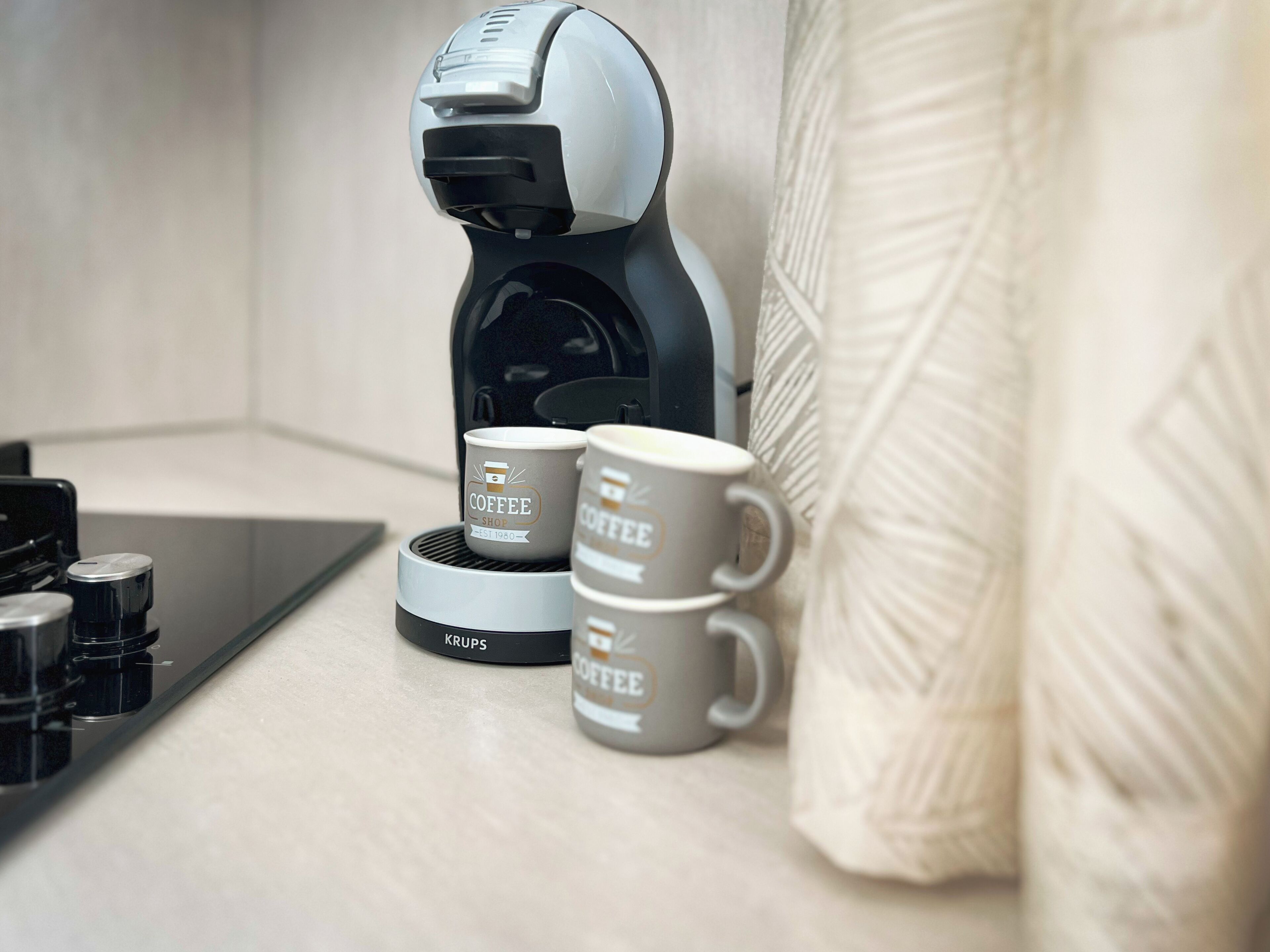 A coffee maker with two coffee cups on a countertop.
