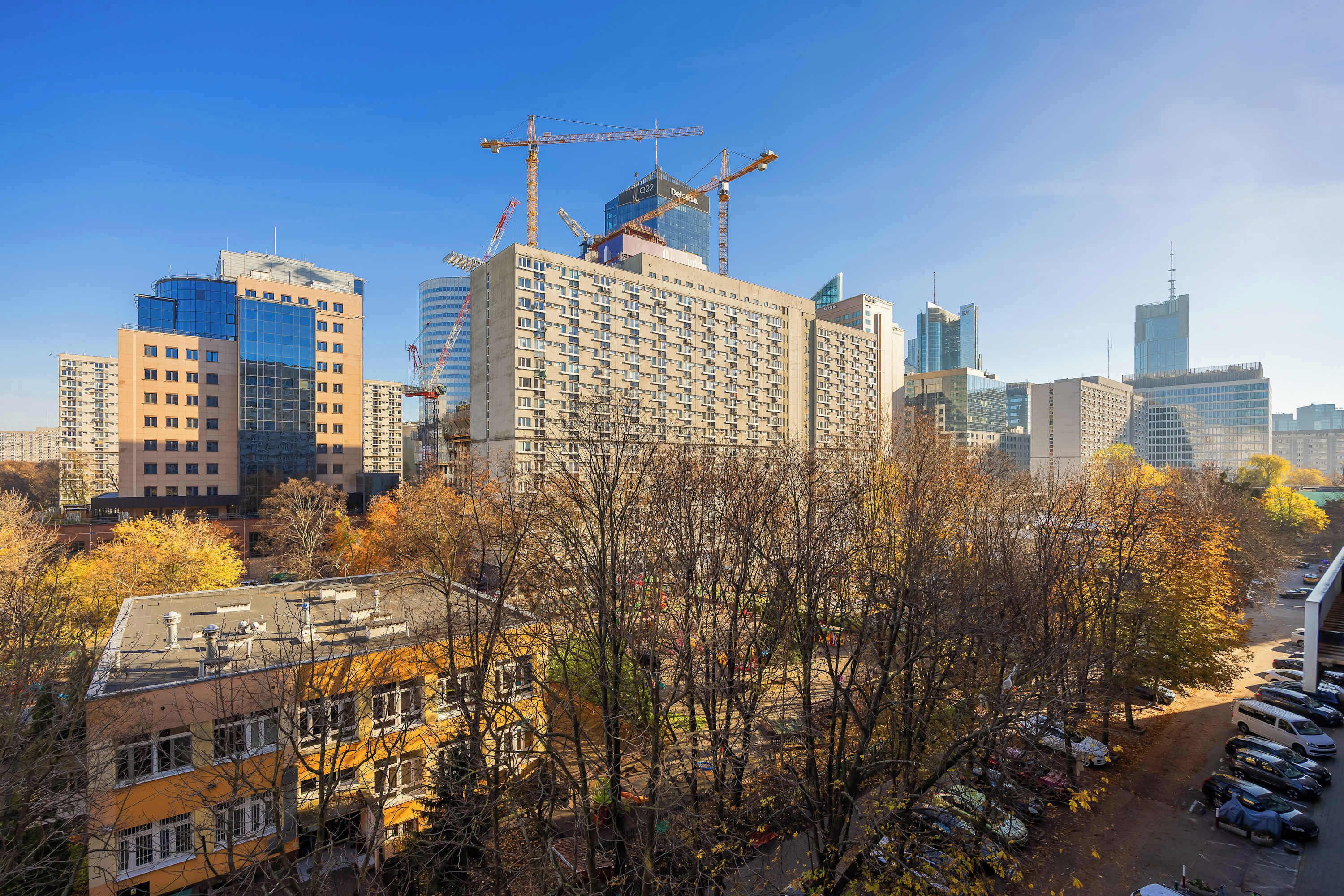 A cityscape with high-rise buildings, including a construction site with cranes.