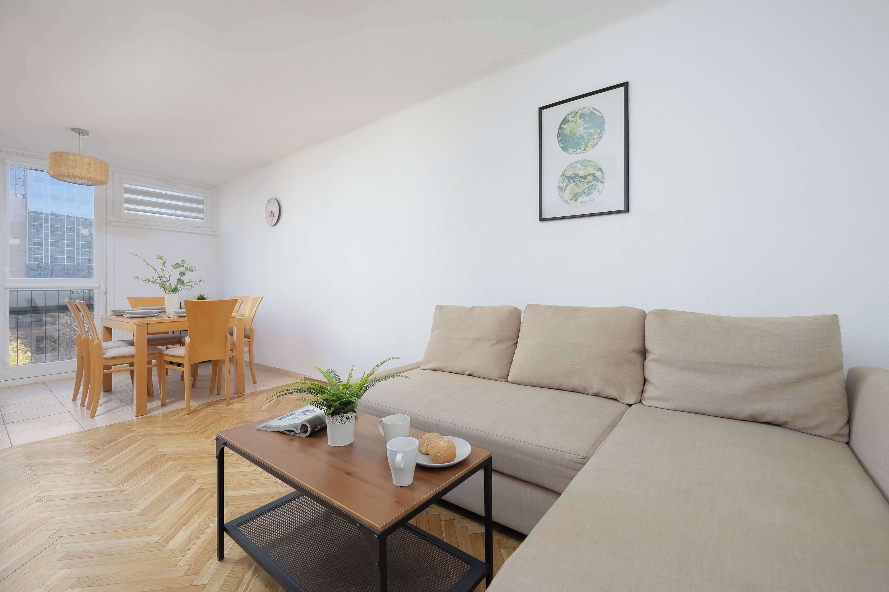 A modern living room with a sofa, a coffee table, and a dining area with chairs and a table.