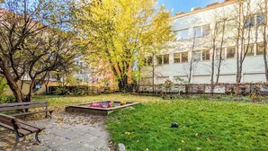 A courtyard with a grassy area, a bench, and a tree with yellow leaves. - Comfortable Apartment | Close to Old Town and Place to Work (Gdańsk)