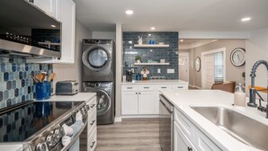Une cuisine moderne équipée d’un lave-linge et d’un sèche-linge intégrés, d’une cuisinière en acier inoxydable et d’un grand évier.