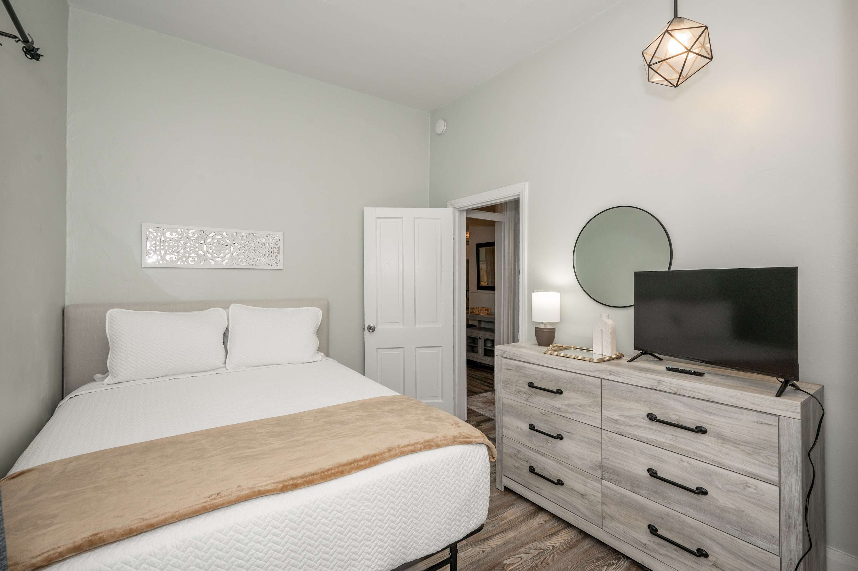 Une chambre à coucher avec un lit, une commode, un téléviseur et un placard.