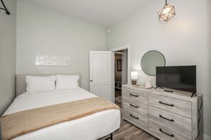 A bedroom with a bed, a dresser, a television, and a closet. - Harrison 3BR | Walk Downtown | Sleeps 6 (Harrison)