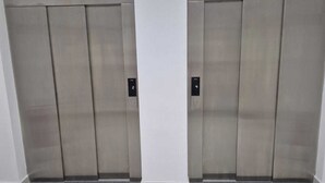 To elevatordøre med metalfinish og en digital skærm på hver dør.