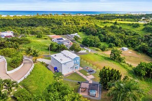 A large, modern house with a spacious backyard, a hot tub, and a view of the ocean. - Oceanview Luxury Villa Near El Yunque w/Hot Tub (Las Coles)