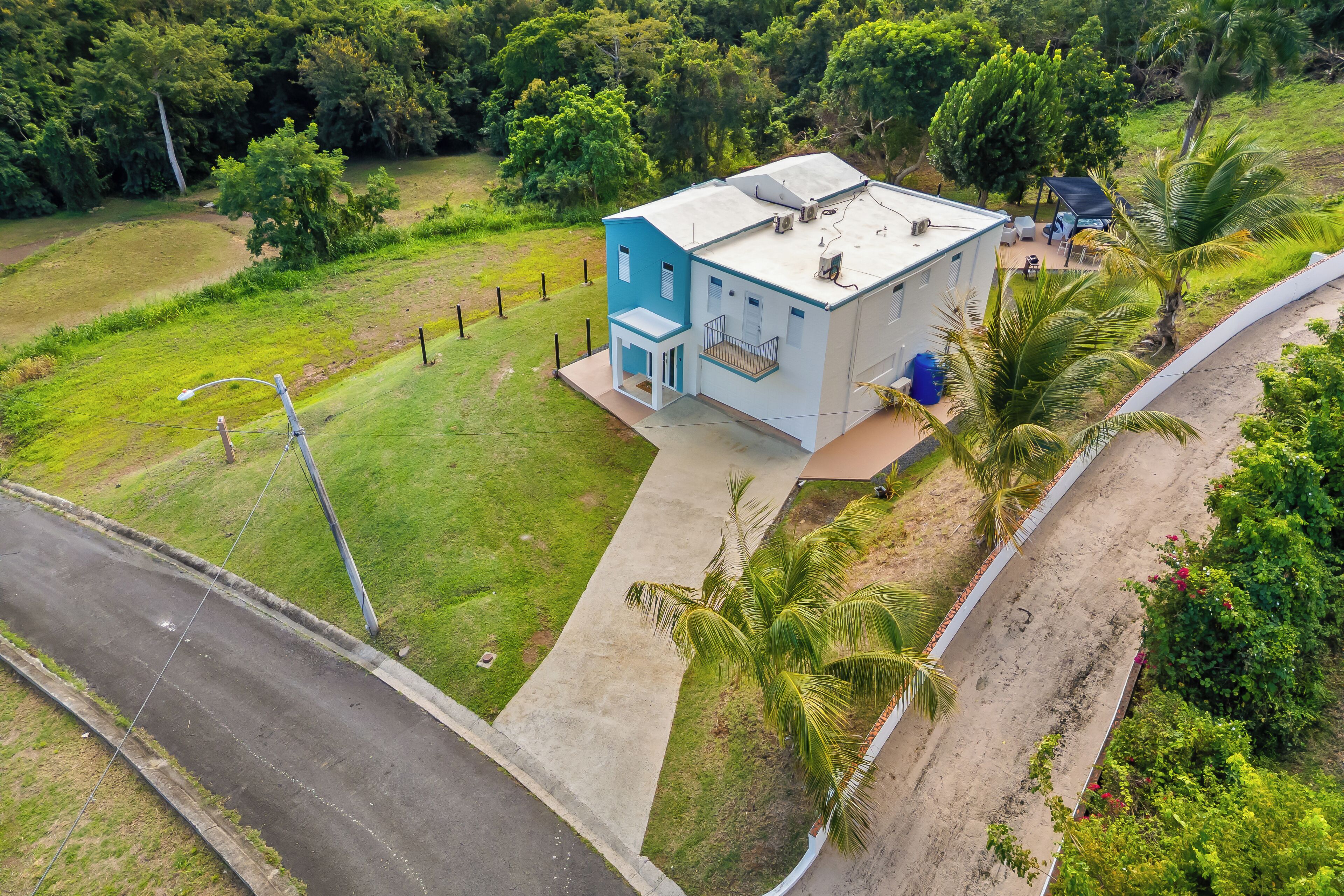 A two-story building with a flat roof, surrounded by lush greenery and a paved driveway.