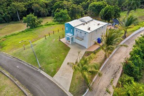 A two-story building with a flat roof, surrounded by lush greenery and a paved driveway. - Oceanview Luxury Villa Near El Yunque w/Hot Tub (Las Coles)