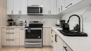 A modern kitchen with white cabinets, a stainless steel oven, a microwave, and a black dish rack. - Oceanview Luxury Villa Near El Yunque w/Hot Tub (Las Coles)