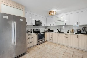 A modern kitchen with stainless steel appliances, light wood cabinets, and a central island. - Oceanview Luxury Villa Near El Yunque w/Hot Tub (Las Coles)