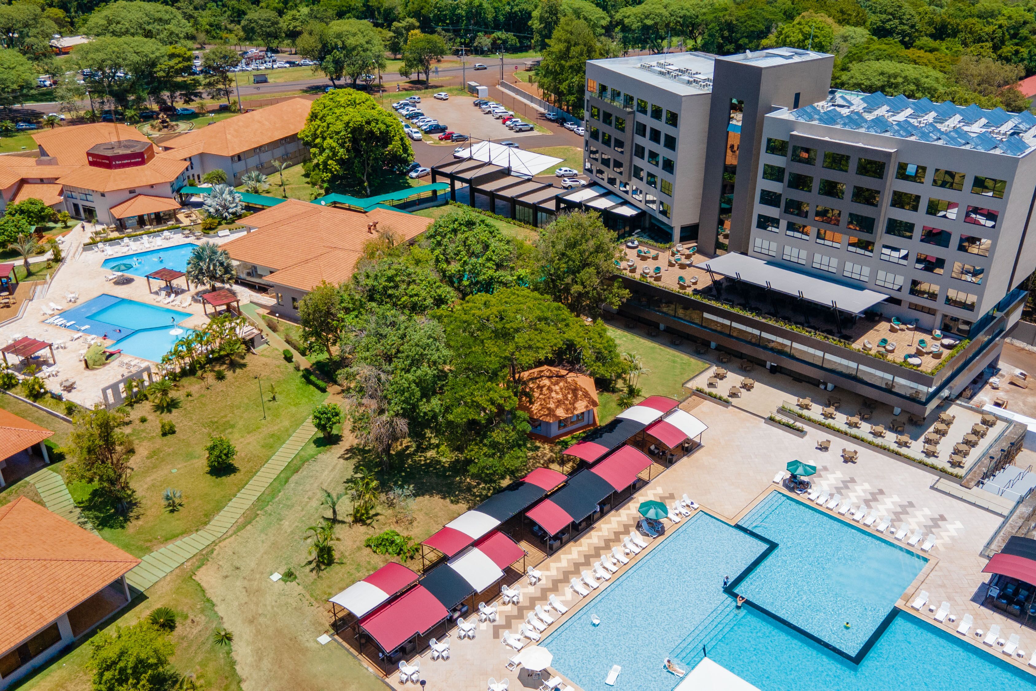 Vista aérea de un resort con varias piscinas, zonas de estar al aire libre y un edificio grande con diseño moderno.