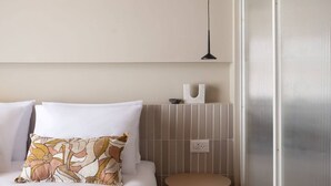 Ein Schlafzimmer mit einem Bett, einem runden Tisch, einer Wandlampe und einem großen Fenster.