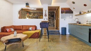 Une cuisine moderne avec un mur recouvert de pierres apparentes, une table à manger en bois et un tabouret de bar.