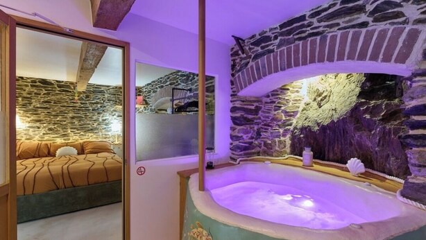 Une salle de spa avec un mur en pierre, une baignoire et un lit donnant sur le mur en pierre.