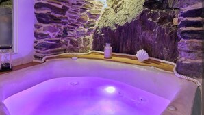 Un bain à remous avec un mur en pierre en arrière-plan et une petite bouteille de lotion.
