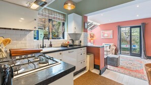 Una cocina moderna con estufa a gas, armarios blancos y un ventanal grande.