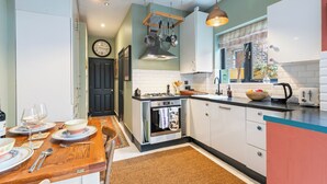 Una cocina con una mesa de comedor de madera, armarios blancos y una ventana que ofrece vistas al exterior.