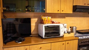 Una cocina con armarios de madera, un tostador, una tetera y un televisor sobre una encimera de madera.