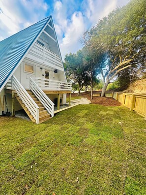 A white barn with a sloped roof, a wooden staircase leading up to the entrance, and a well-maintained grassy yard.