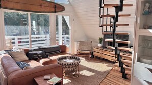 A cozy living room with a brown leather sofa, a round coffee table, and a spiral staircase.