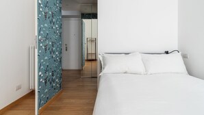 Un dormitorio con cama, armario y baño visible a través de una puerta abierta.