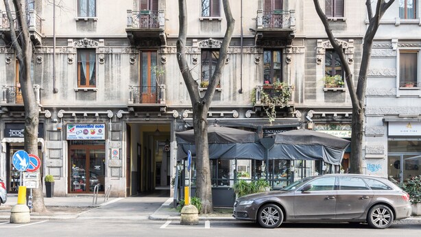 Un edificio con escaparate que dice "marcelini auto" y un coche estacionado.