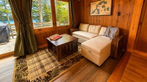 Interior de una cabaña de madera con un sofá, una mesa y un mapa en la pared.