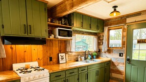 Una cocina con gabinetes verdes, una estufa blanca y piso de madera.