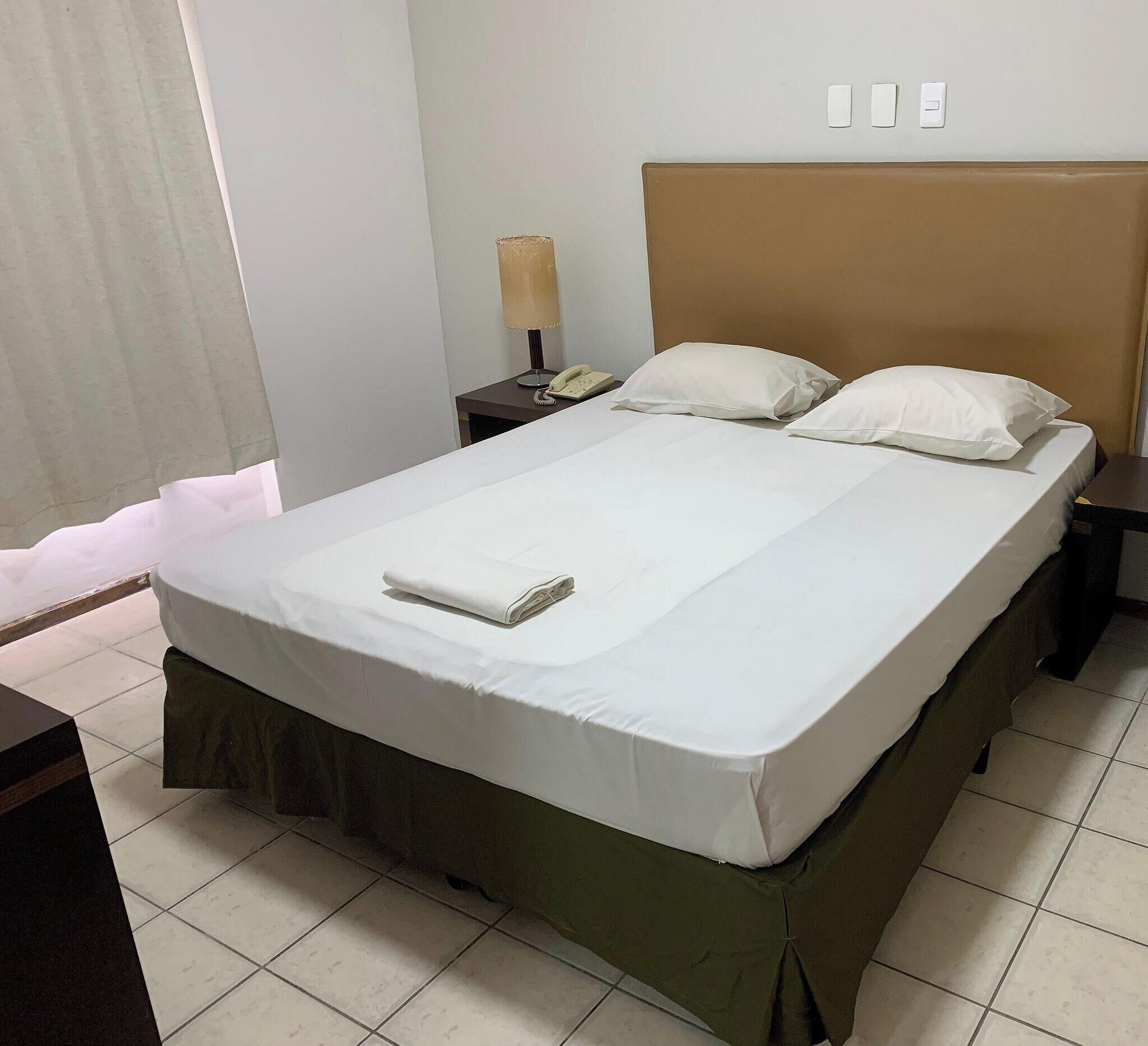 Una habitación de hotel con una cama, una mesita de noche, una lámpara y un teléfono.