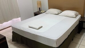 A hotel room with a bed, a nightstand, a lamp, and a telephone.