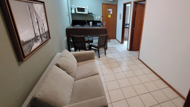 A living room with a sofa, a dining area with a table and chairs, and a kitchen area with a microwave.