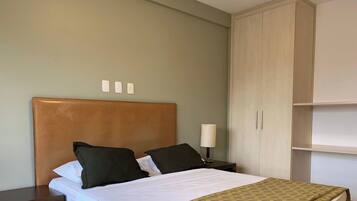 A hotel room with a bed, a nightstand, a lamp, and a wardrobe.
