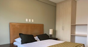 A hotel room with a bed, a nightstand, a lamp, and a wardrobe.