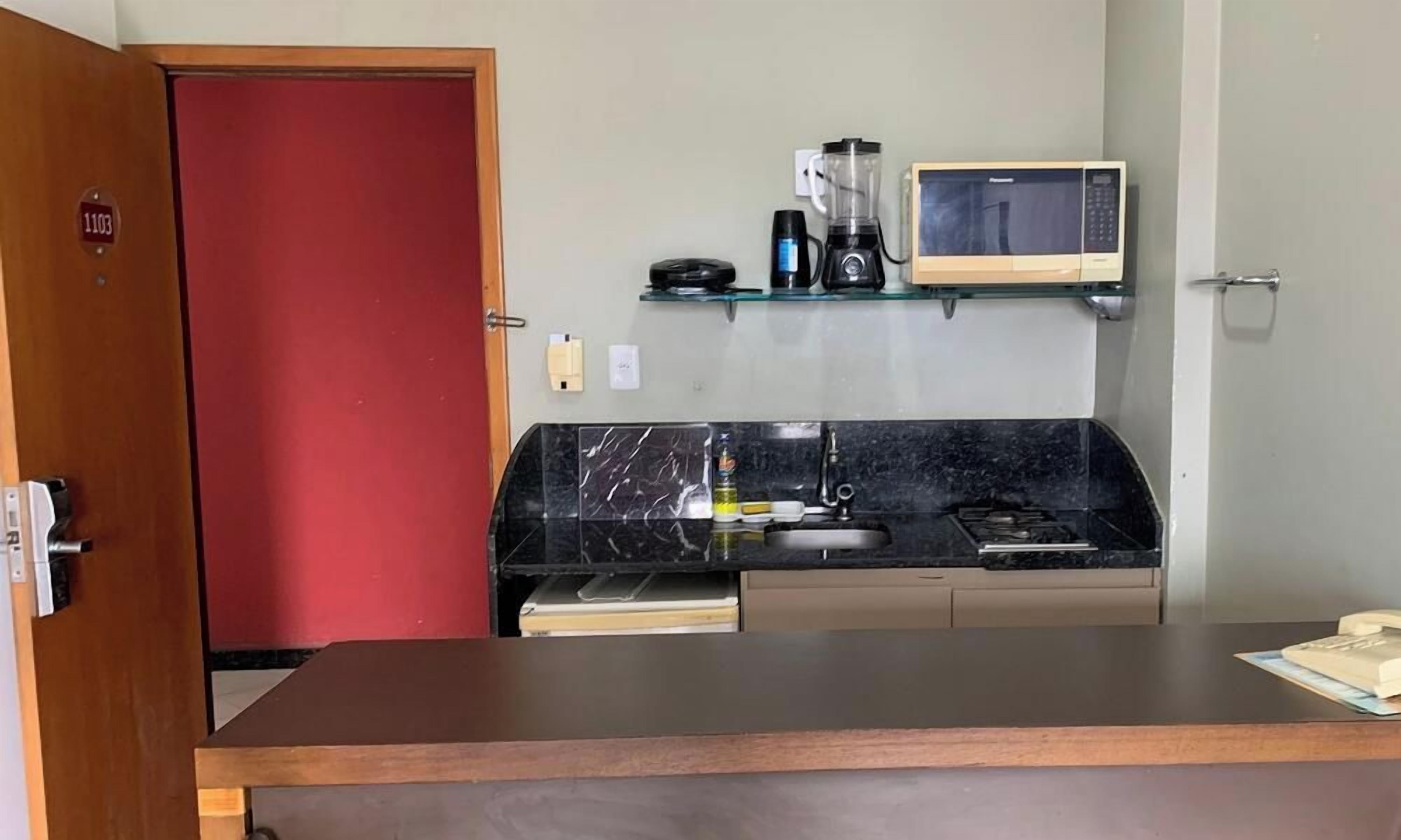A compact kitchenette with a microwave, coffee maker, and a small shelf.
