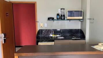 A compact kitchenette with a microwave, coffee maker, and a small shelf.