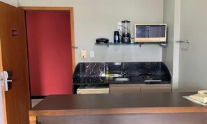 A compact kitchenette with a microwave, coffee maker, and a small shelf.