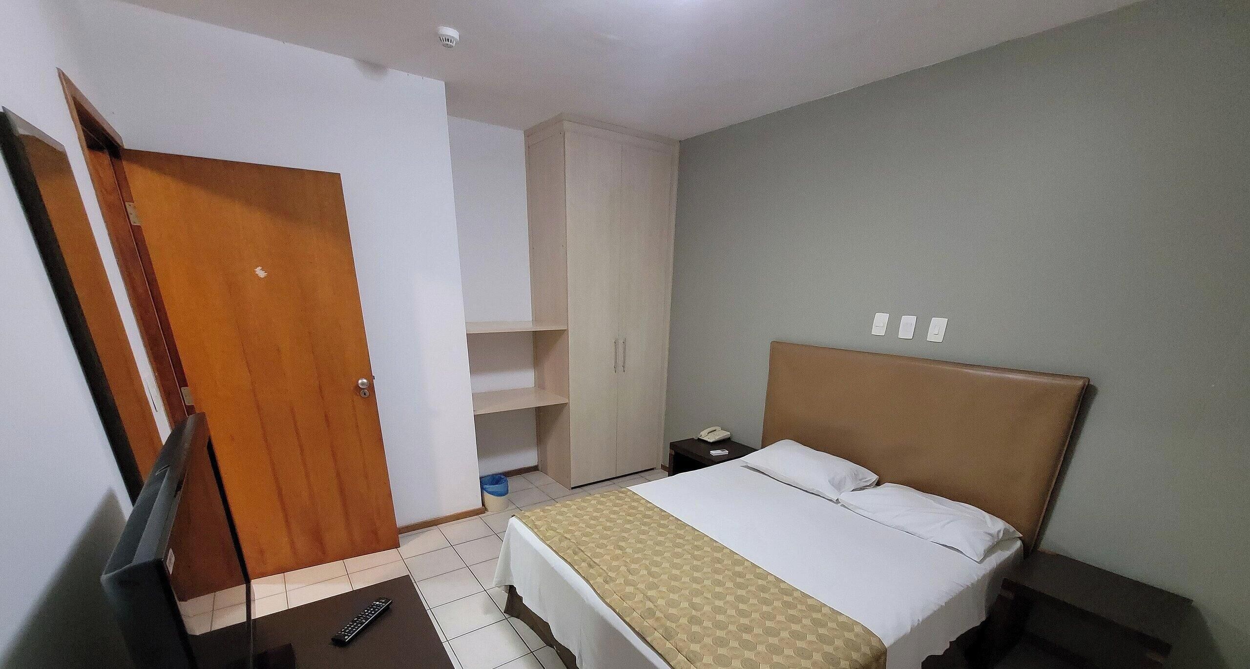 Une chambre d’hôtel comprenant un lit, une table de chevet, un bureau, une armoire et une porte.
