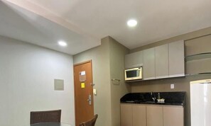 A compact kitchen with a microwave, refrigerator, and a door with a lock.