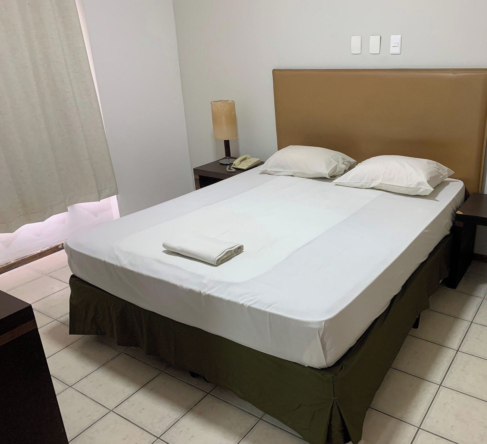Una habitación de hotel con una cama, una mesita de noche, una lámpara y un teléfono.