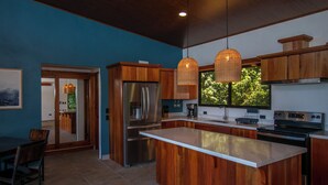 A modern kitchen with wooden cabinets, stainless steel appliances, and pendant lighting. - 3-bedroom villa in Platanillo, ocean & mountain view! (Platanillo)