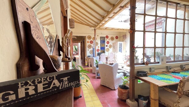 A cozy interior with a wooden ceiling, a large window with bars, and a variety of decorative items on the walls. - Coliving Granada (Envigado)