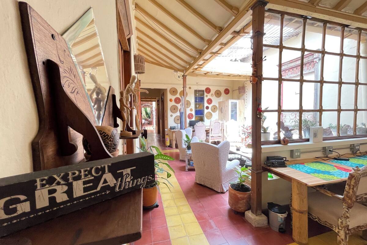 A cozy interior with a wooden ceiling, a large window with bars, and a variety of decorative items on the walls.