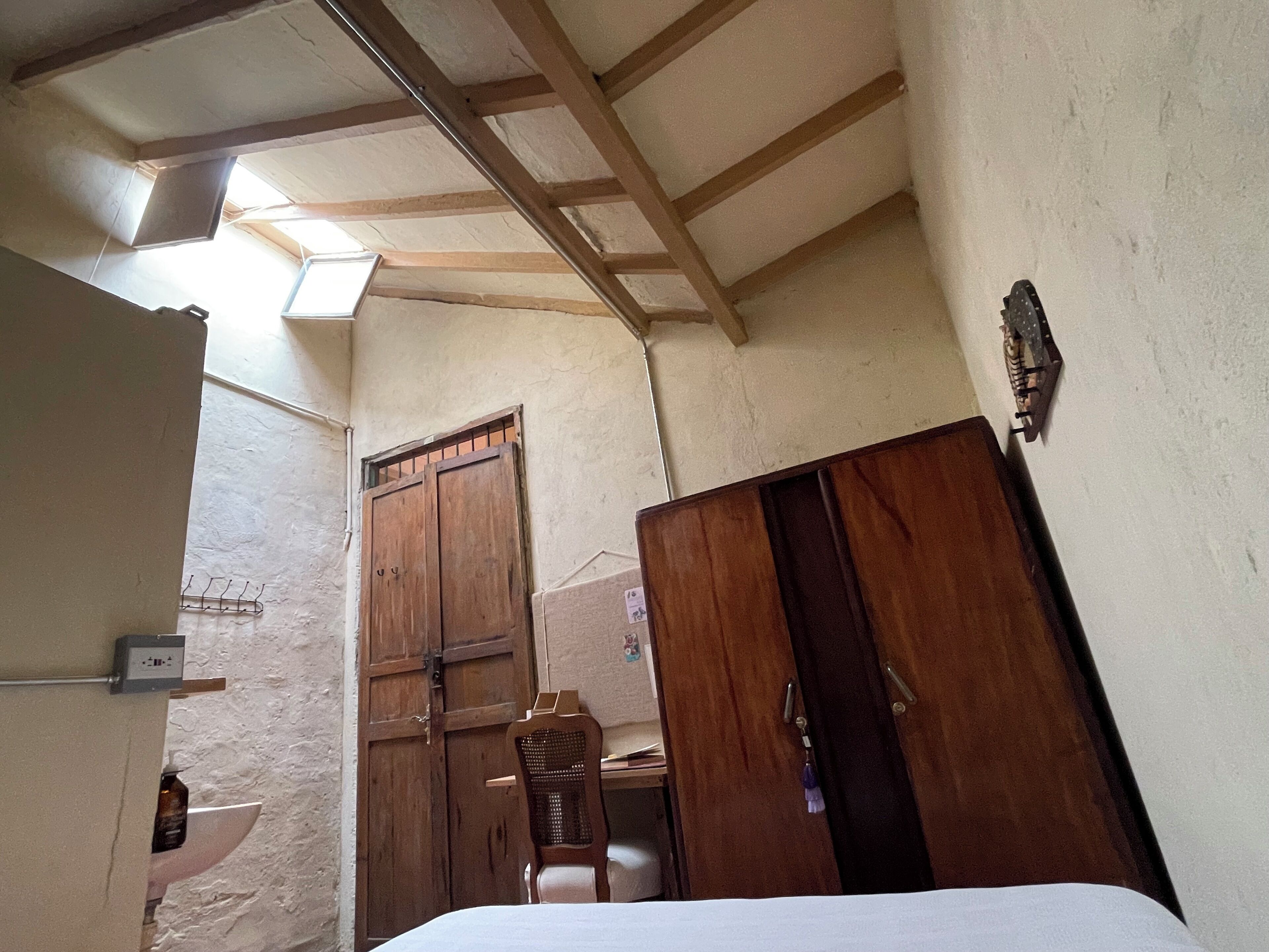 Een kamer met een houten garderobe, een stoel en een bed.