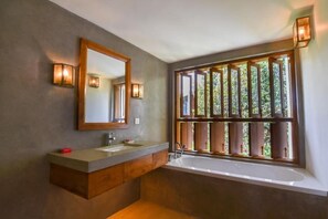 Moderni kylpyhuone, jossa on suuri peili, kaksi pesuallasta ja kylpyamme.