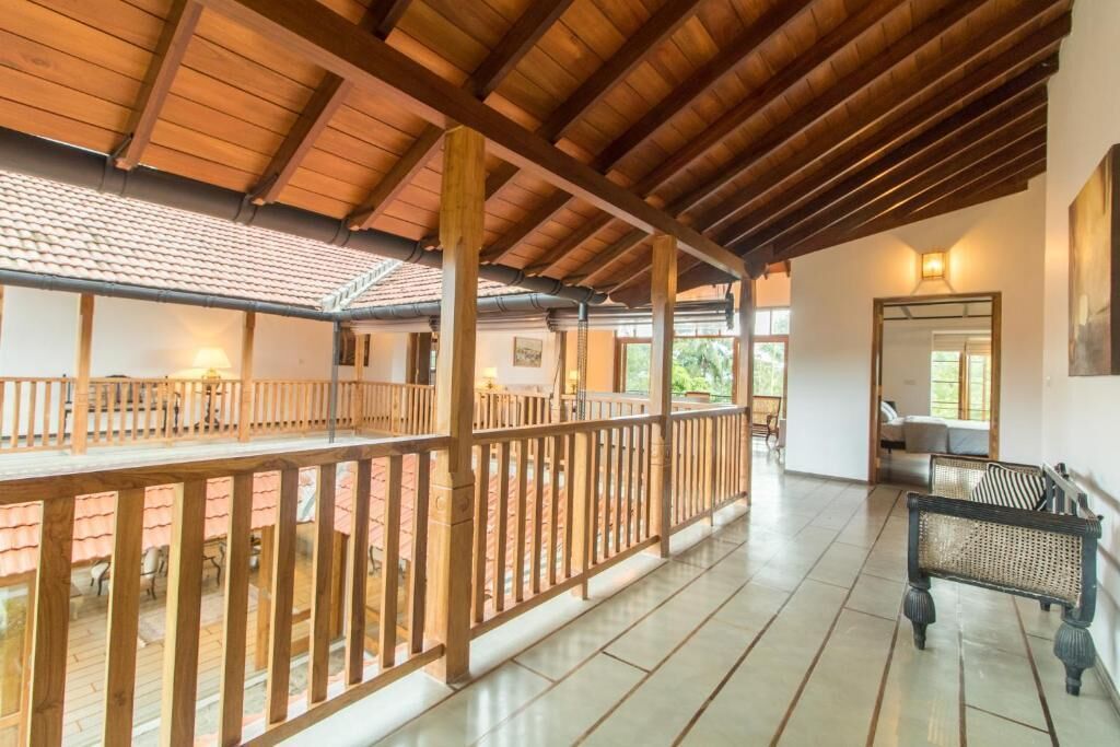 Un espacio al aire libre techado con barandillas de madera, un banco y piso de baldosas.